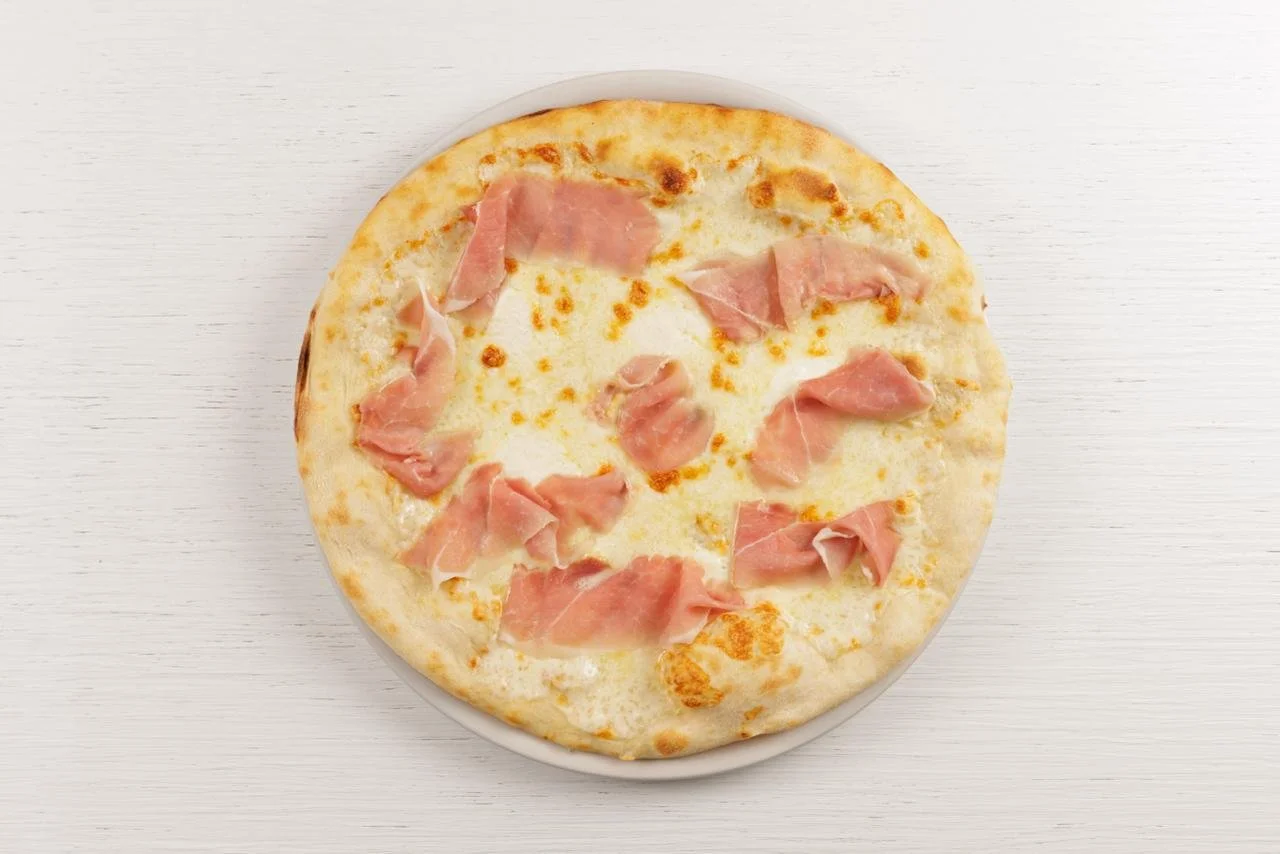 Pizza bianca con prosciutto cotto, formaggio sopra una superficie bianca