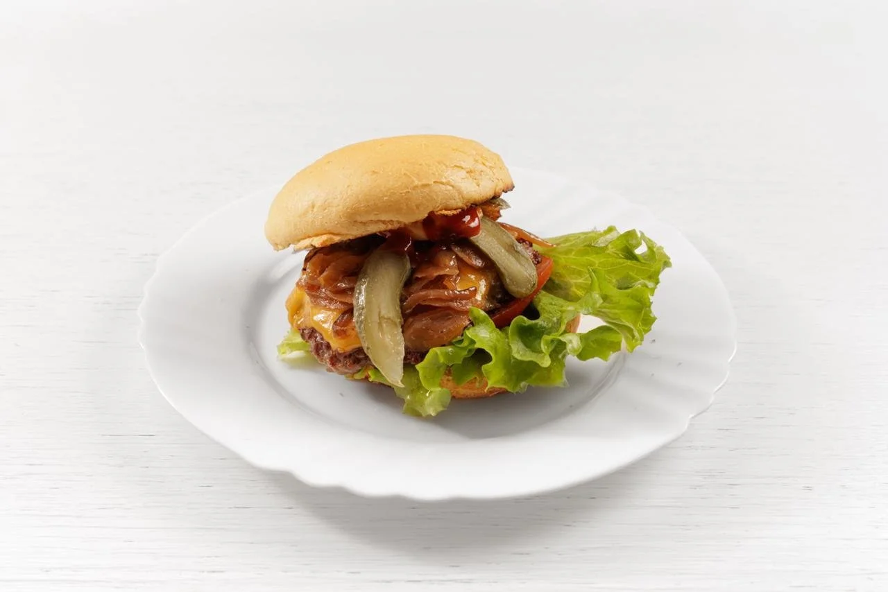 Sandwich con carne, insalata, cetrioli e pomodoro, servito su un piatto bianco