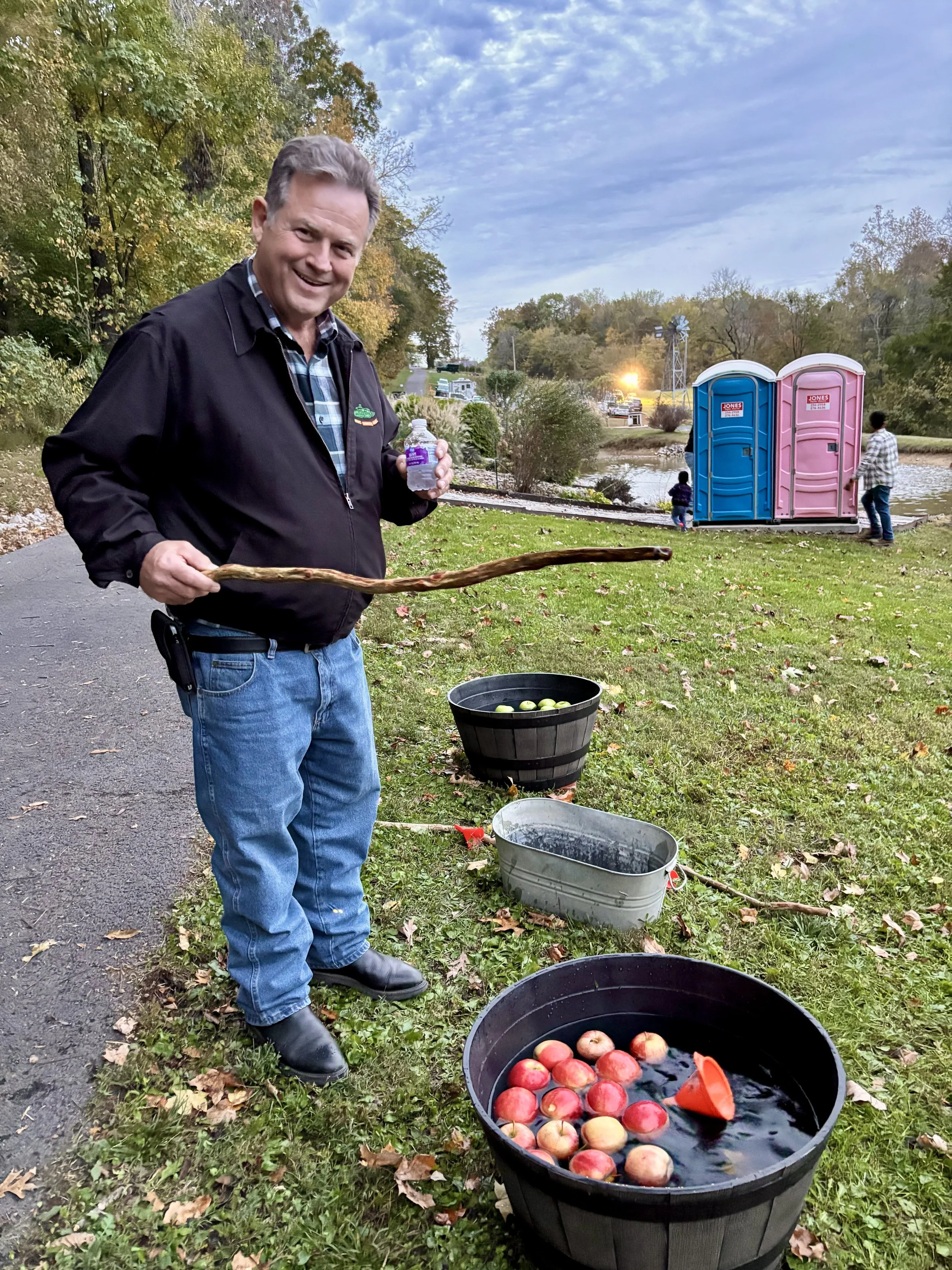  Man playing apple fishing game at festival holding bottle of flavored water 