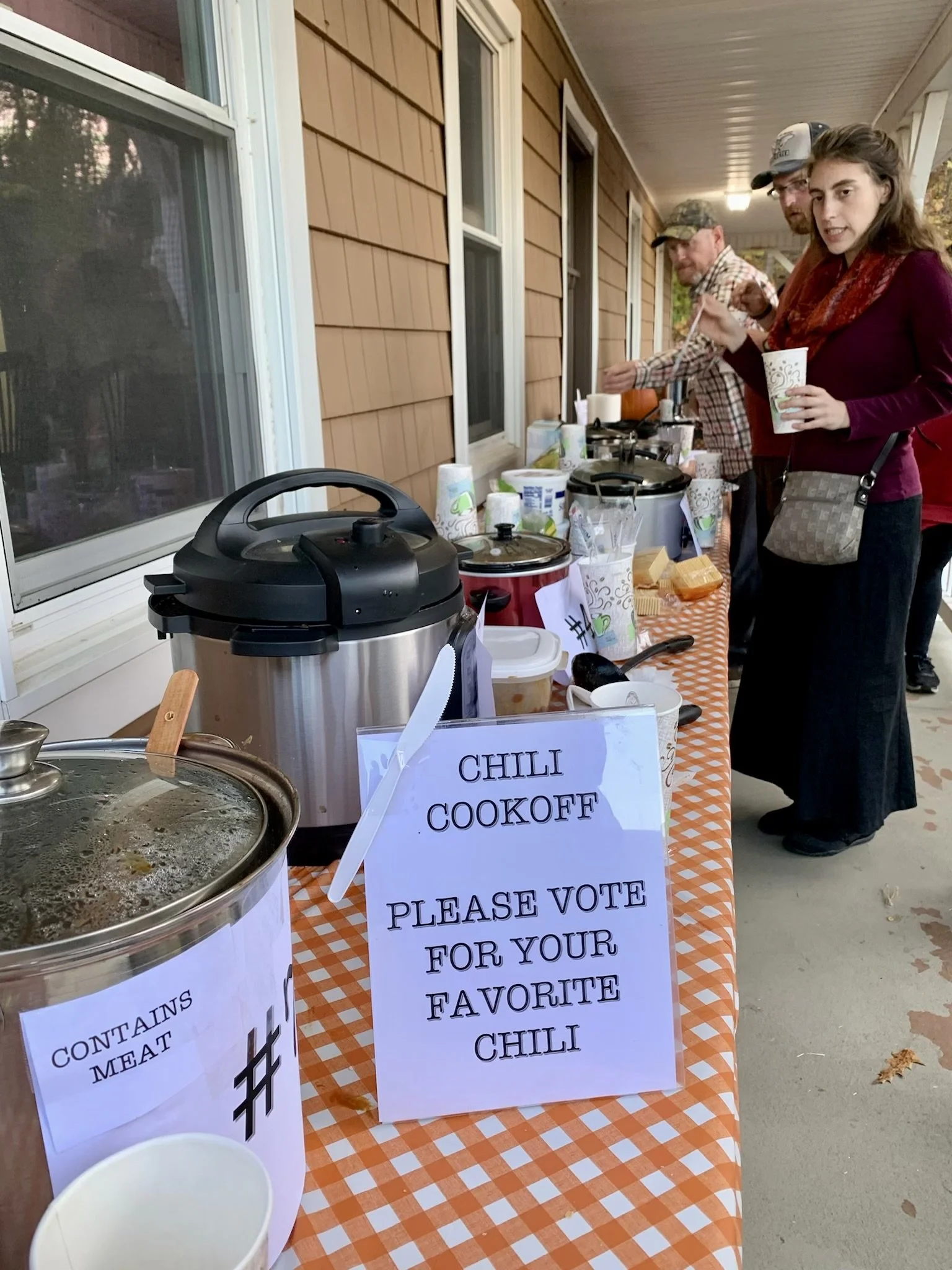  People at a table of food showcasing a chili cookout 