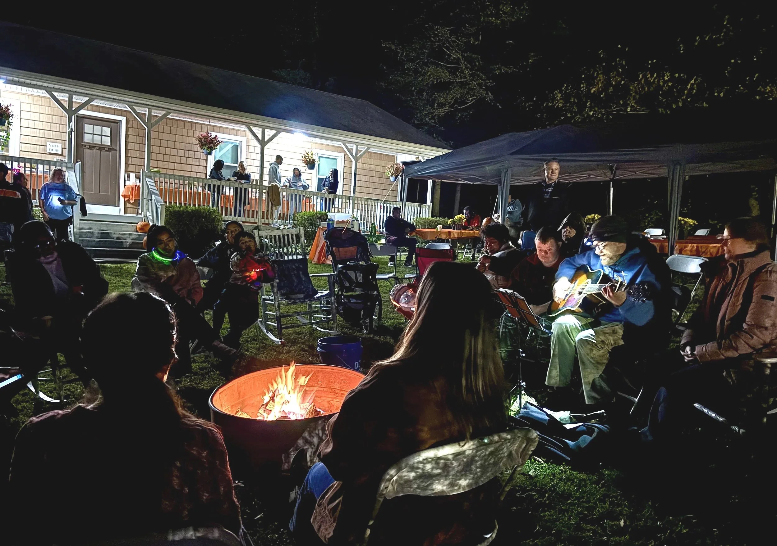  Group of people around a bon fire singing with guitar accompaniment, at night 