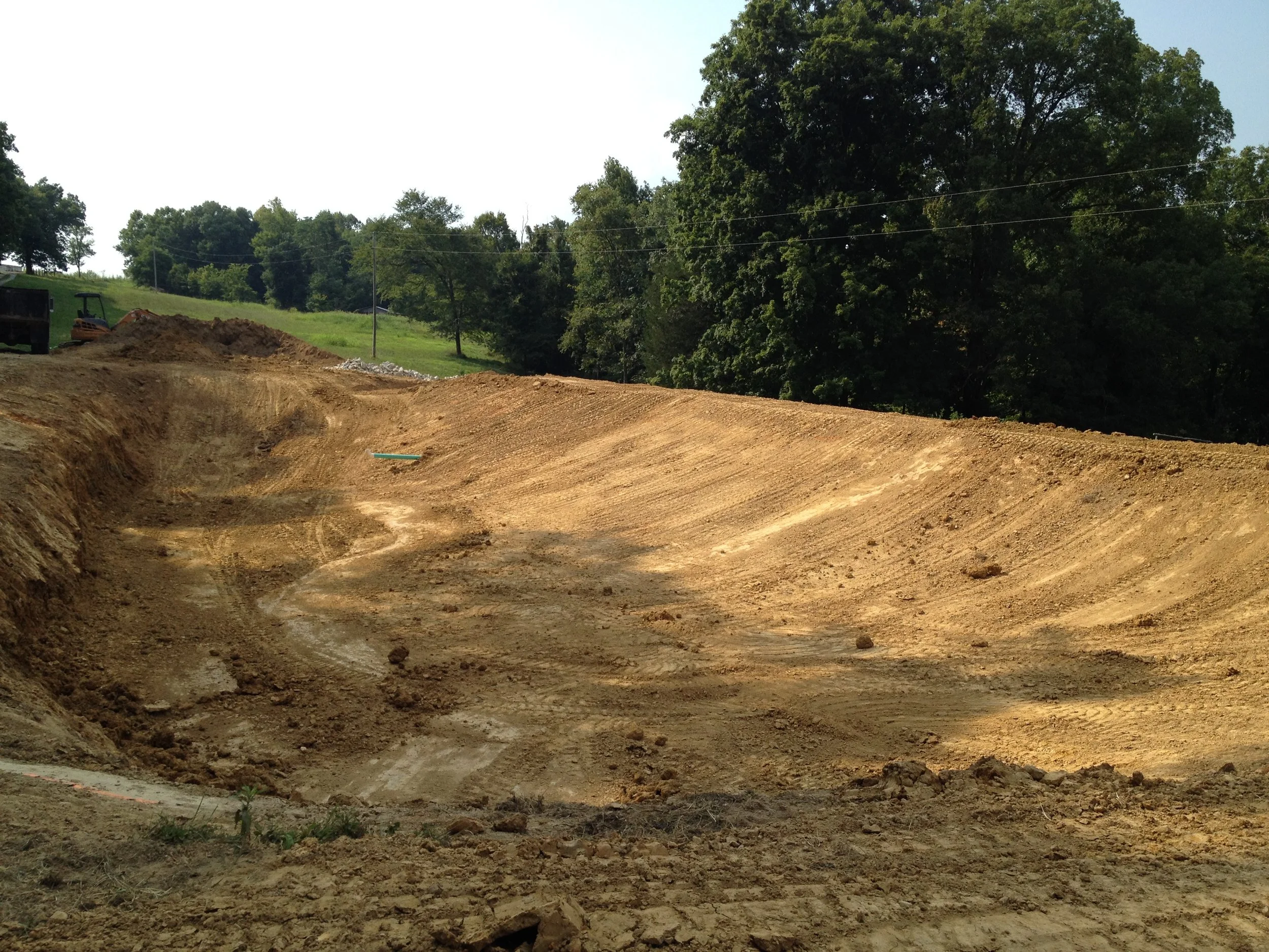 Bulldozer digging pond in country setting