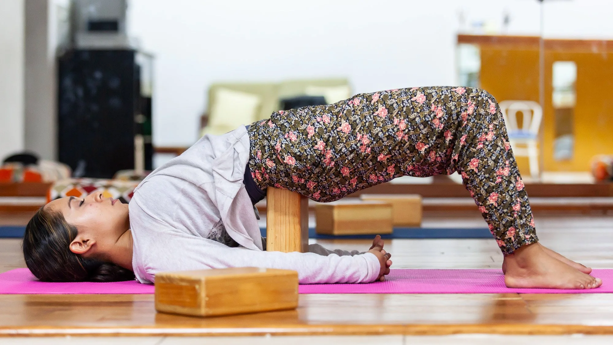 L'accompagnement bienveillant. L'usage des accessoires comme le bloc de yoga illustre une pratique tournée vers le confort et l'alignement profond.