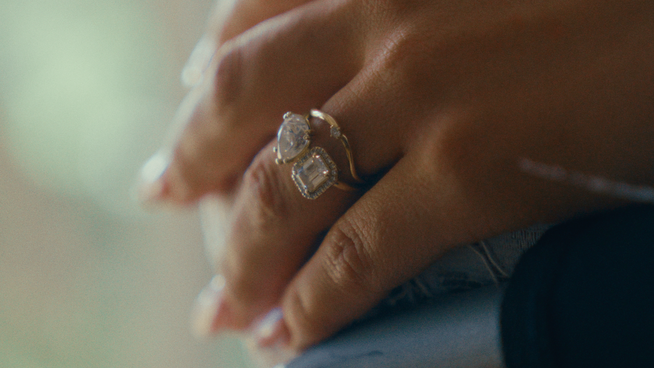 Close-up of a hand wearing a silver ring with a large, clear gemstone and smaller gemstones around it.
