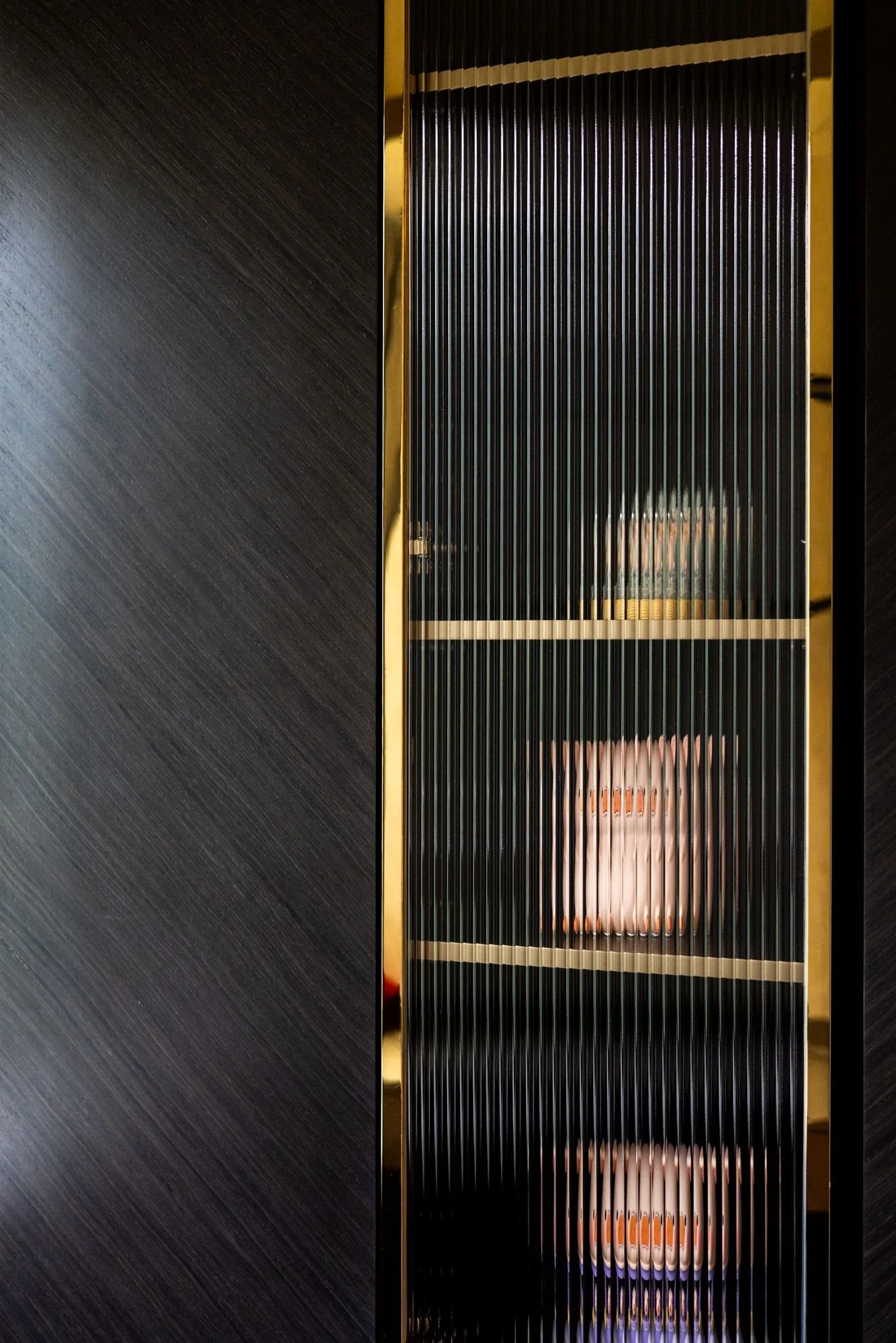 Reflection of a person taking a photo on a textured glass door, with dark interior framing.