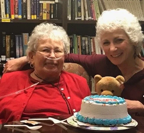 Dr. Michele Haber celebrating a birthday in-home with a smiling senior patient beside a birthday cake.