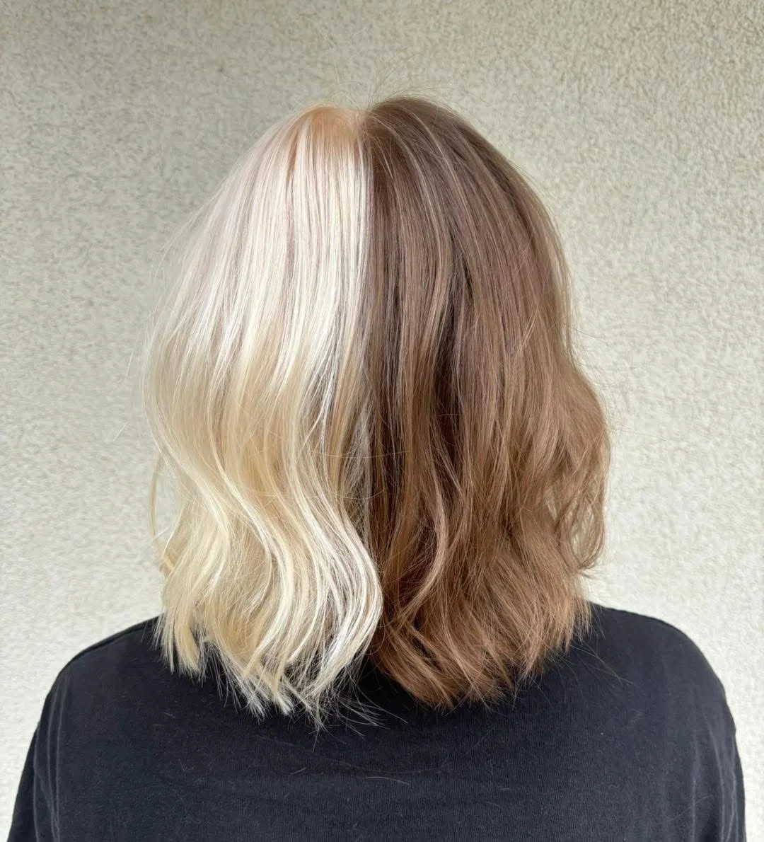 Half of the person's hair is platinum blonde styled in loose waves, and the other half is light brown with a wave pattern.