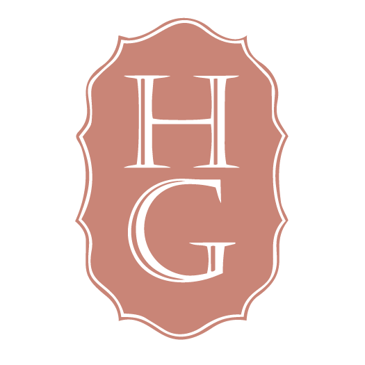 A pink badge with a decorative border displaying the initials 'HCG' in white uppercase letters.