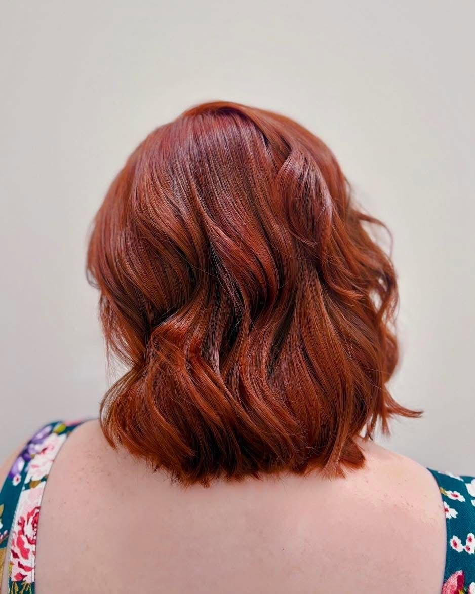 Back view of a woman's shoulder-length red curly hair.