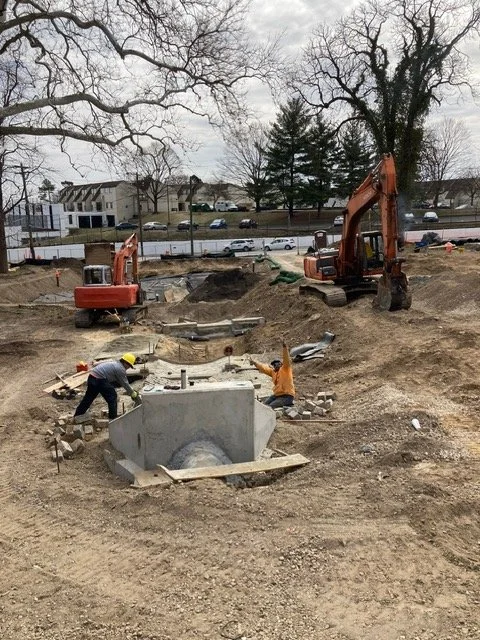 Construction site with two excavators and workers installing or repairing a concrete structure.