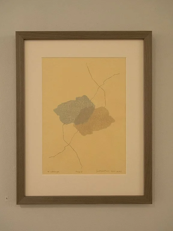 A framed artwork featuring an abstract map with two landmasses connected by roads, on a yellow background.
