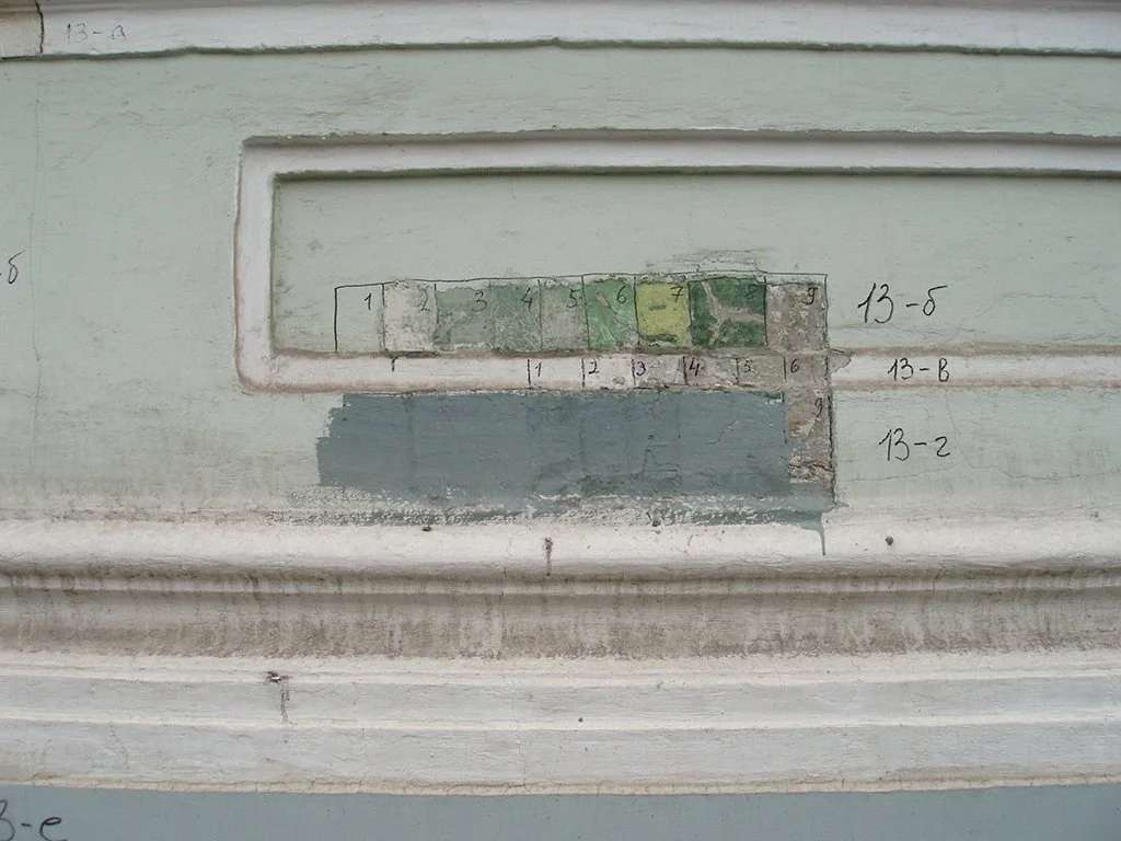 A section of a building wall with a faded, incomplete map or diagram with handwritten labels and numbers.