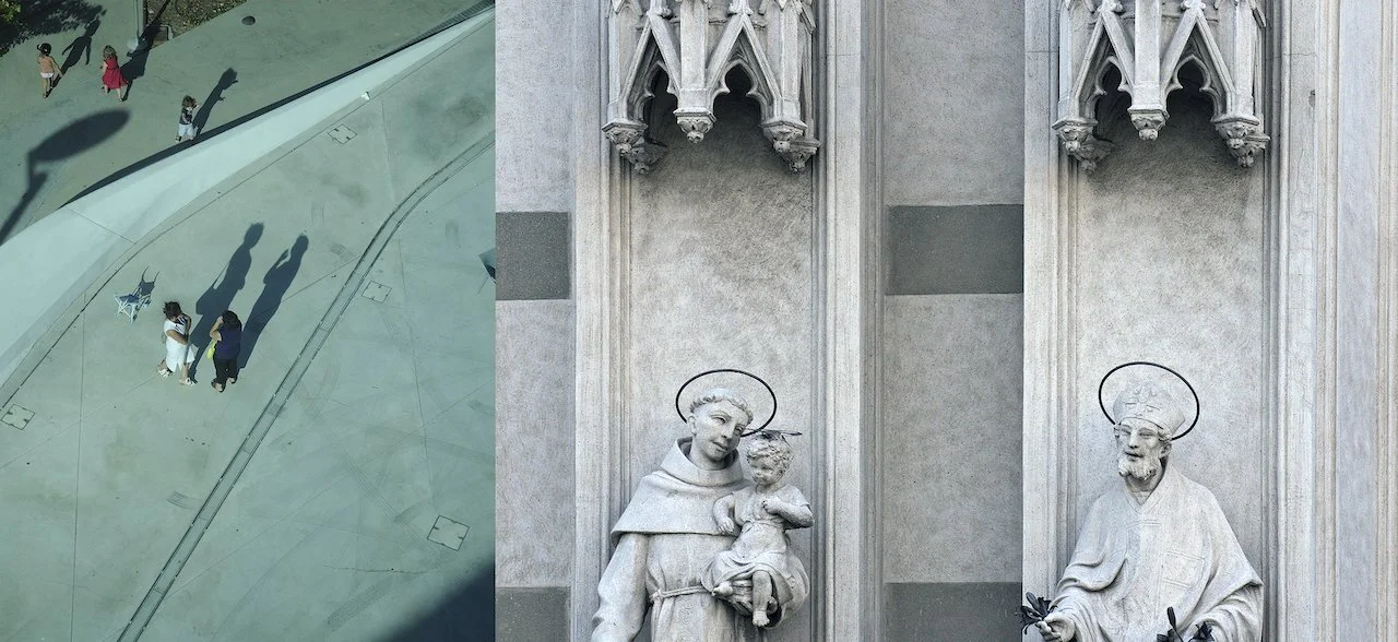 Reflection of people walking and standing in a modern glass building, with a church sculpture of St. Anthony holding Baby Jesus visible on a gray stone wall.