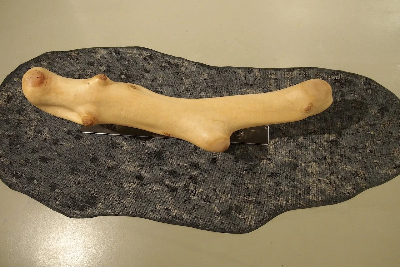 A piece of raw ginger root placed on a dark textured surface.