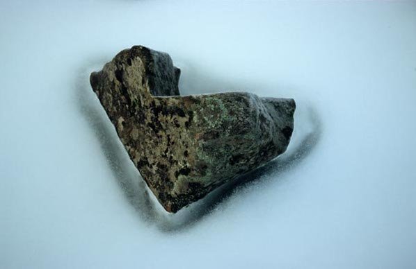 A small, irregularly shaped rock with a rough surface, placed on a plain white background.