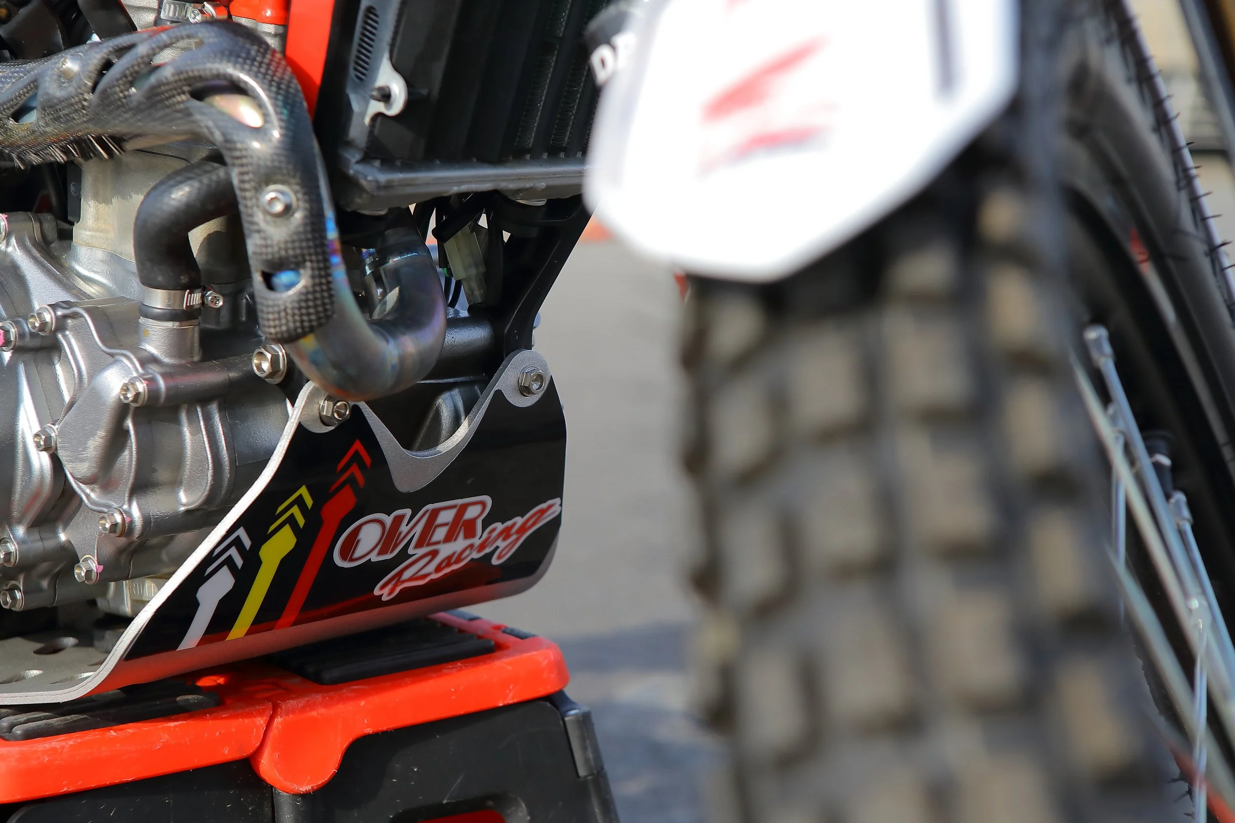オフロードバイクのエンジンとタイヤの部分。ブラックのプレートに「OMER Racing」のロゴ入り。