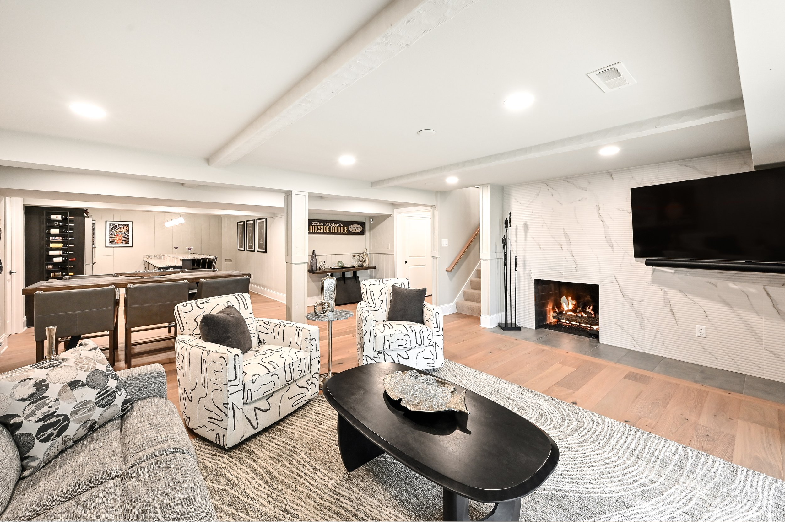 Living room with a fireplace, TV, armchairs, sofa, and wooden flooring