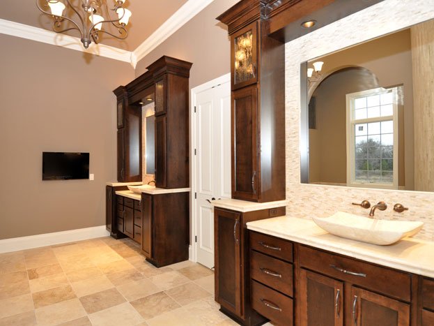 Bathroom with dark wood cabinets, a large mirror, a vessel sink, and a window to the outside.