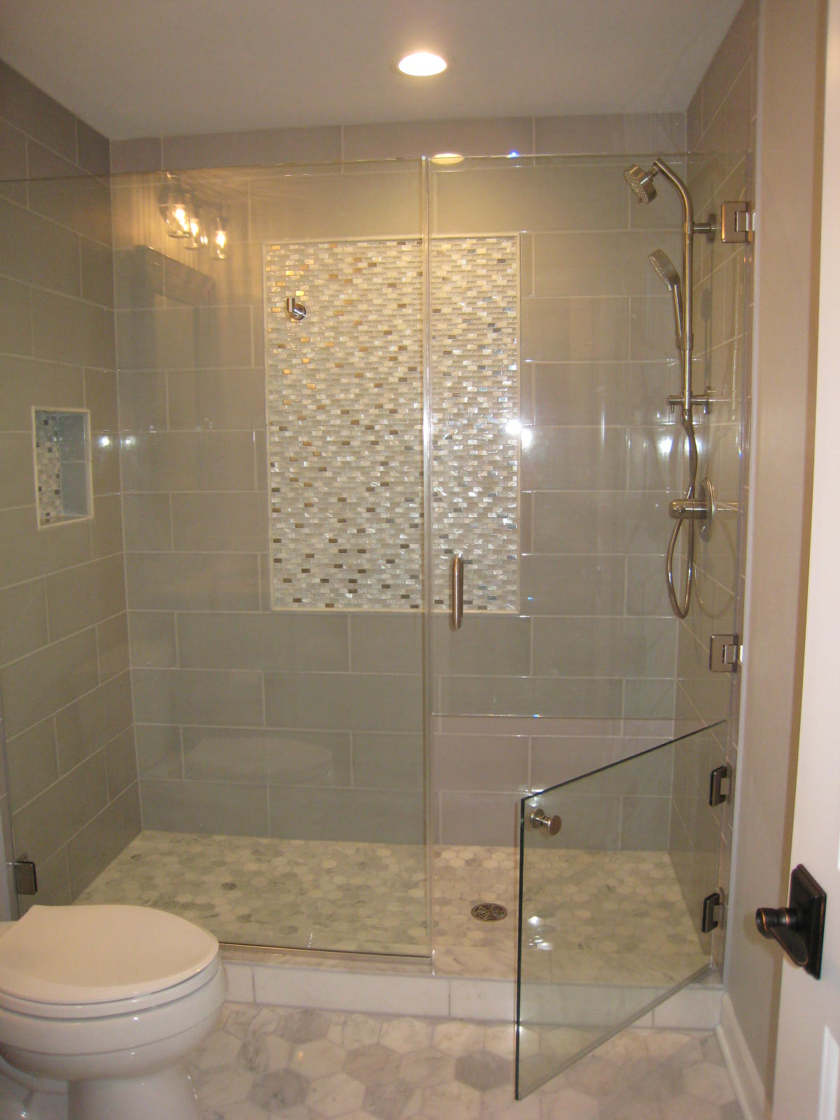 Bathroom with a glass shower enclosure, tiled walls, and a toilet.