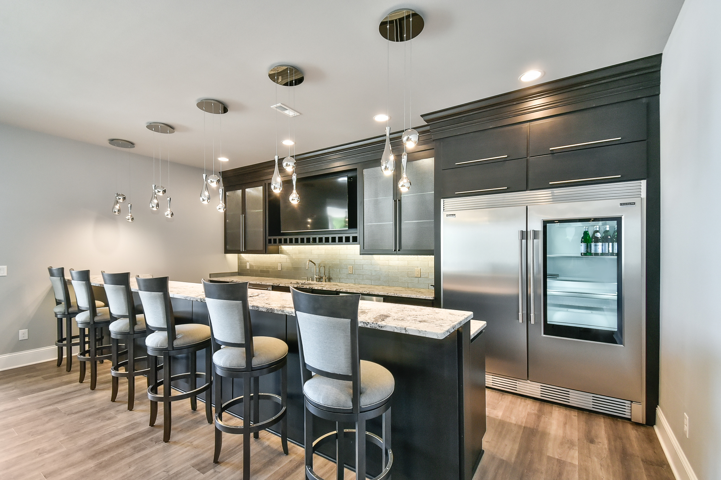Modern kitchen with a granite island, black cabinets, and stainless steel appliances, including a wine cooler.