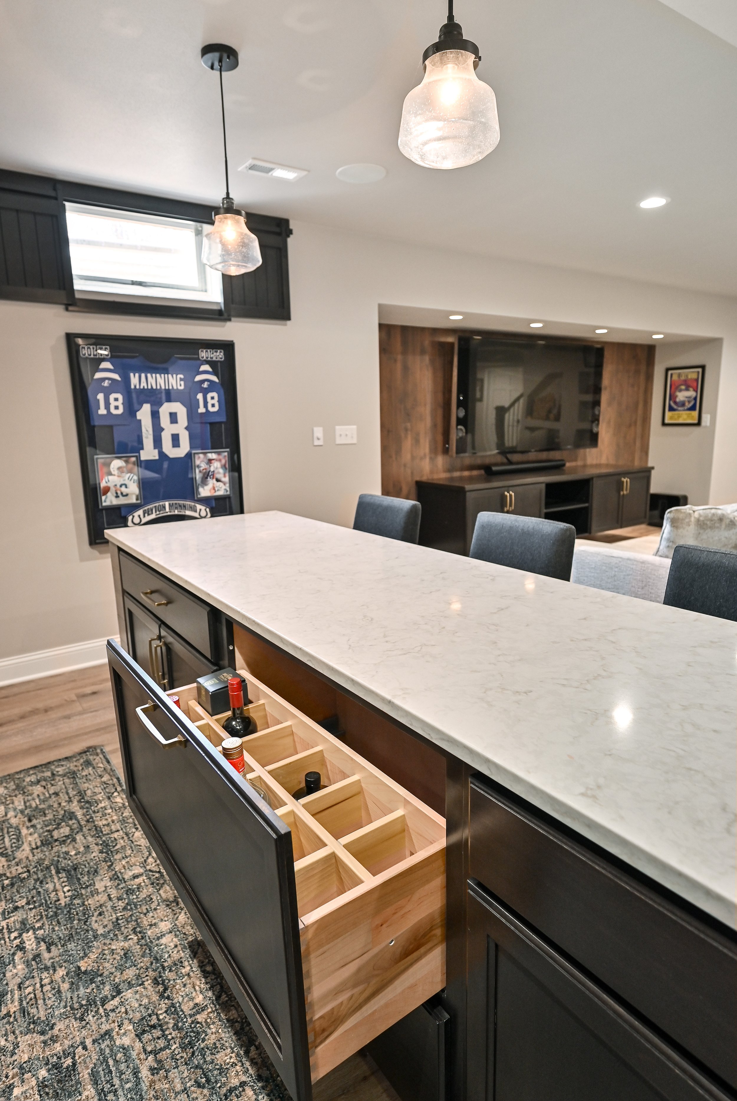 Modern kitchen with a marble island, open shelving, and a framed sports jersey on the wall.
