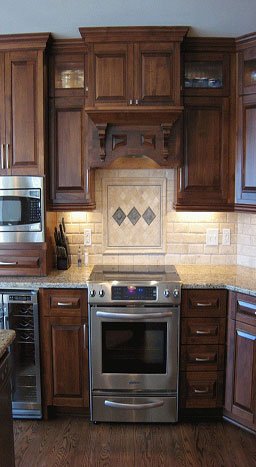 Kitchen with wooden cabinets, beige tiled backsplash with diamond shapes, stainless steel oven, microwave, and countertop appliances.