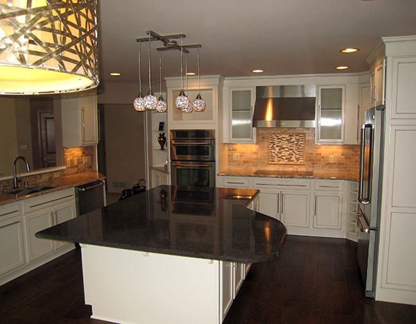 Modern kitchen with white cabinets, a black countertop island, stainless steel appliances, and pendant lights over the island.