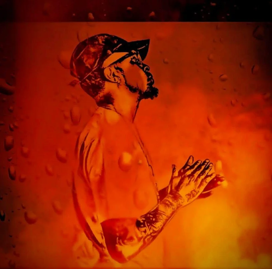 An illustration of a man with a beard and tattoos, wearing a cap and sunglasses, standing with his hands clasped together, set against a textured orange background.