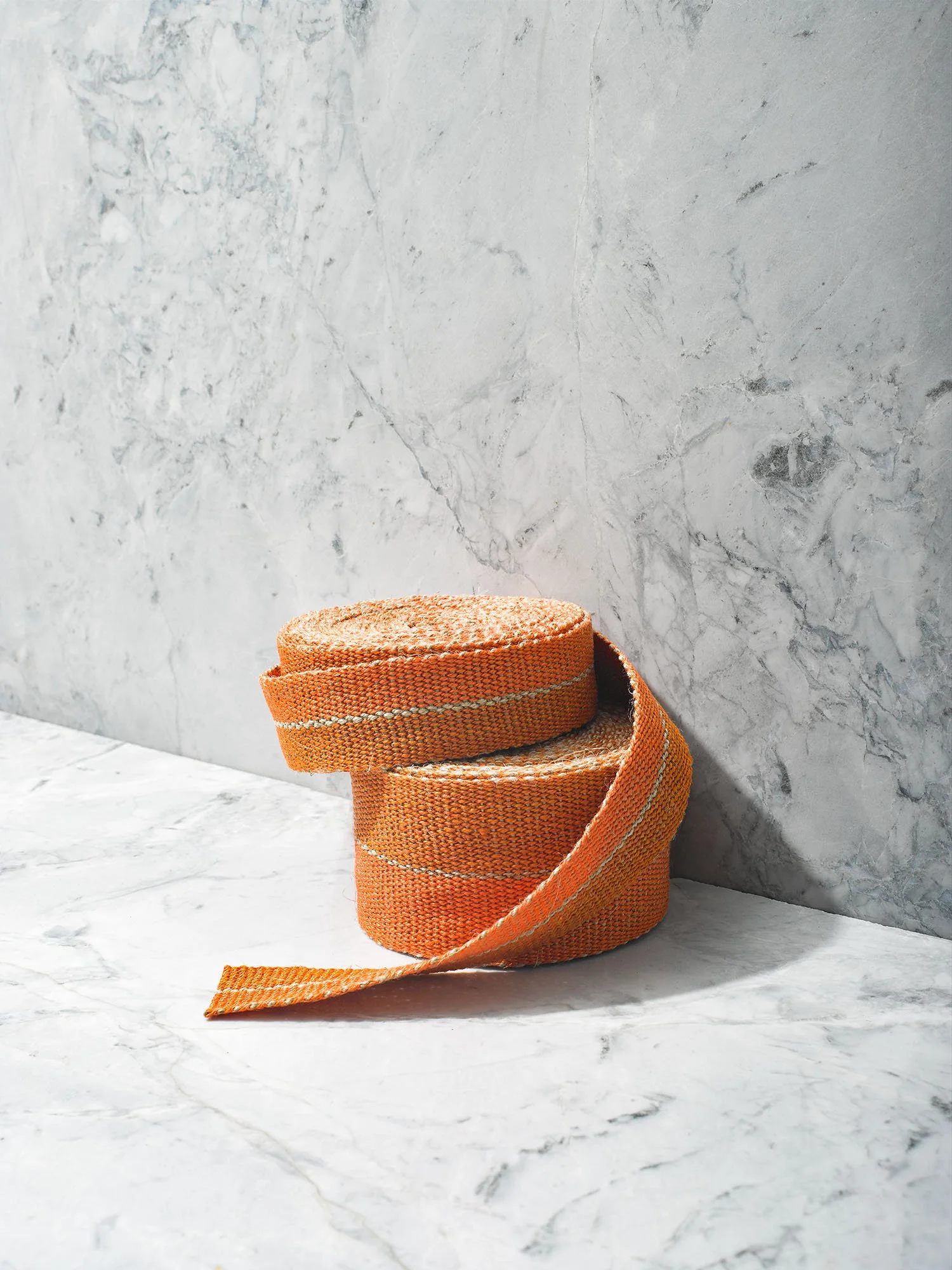 Stack of Potimarron handwoven linen tape trim in two oranges divided by a pinstripe of flax in narrow and medium widths.