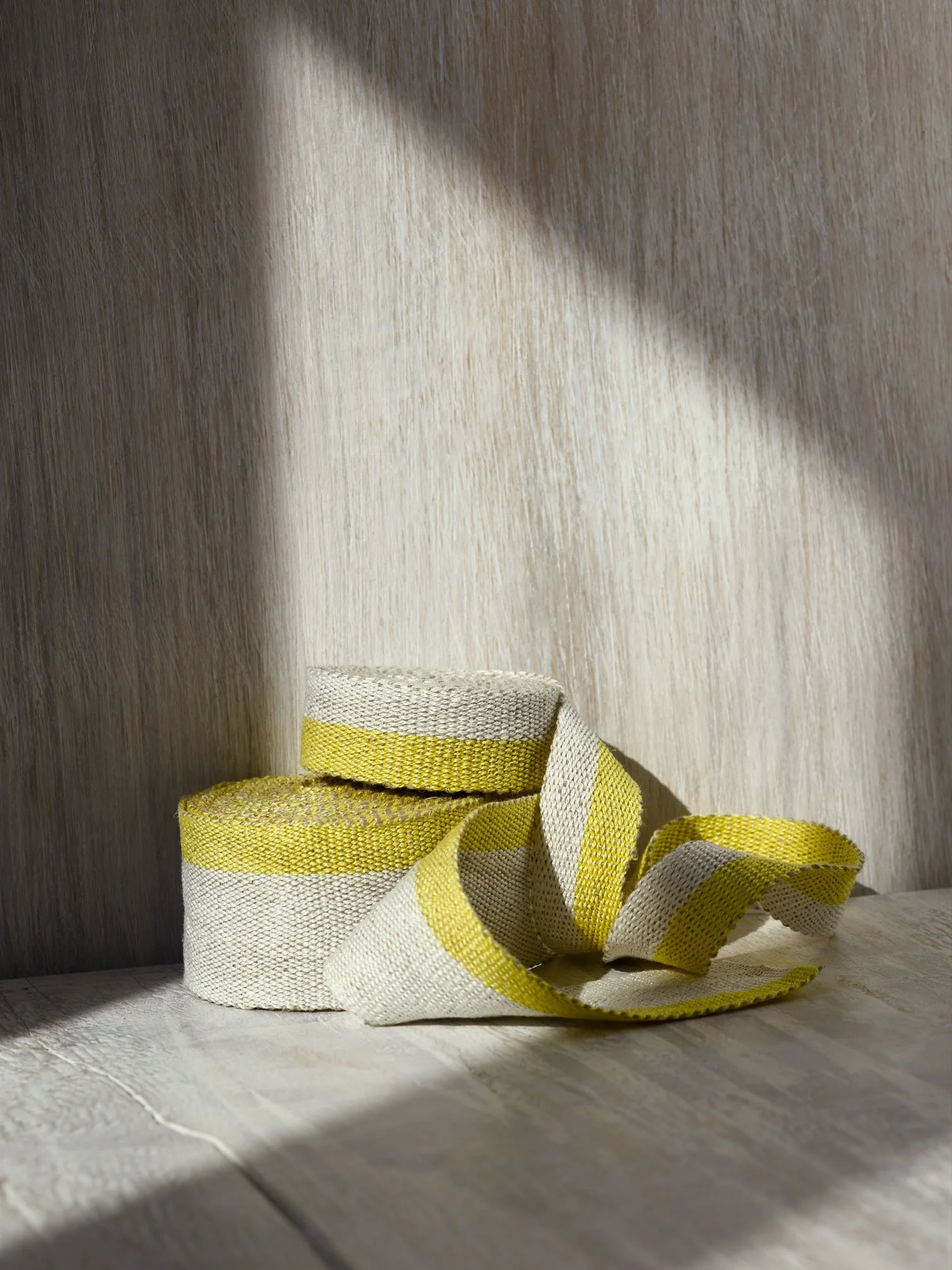 Stack of Fresh Yellow handwoven linen tape trim in a soft, bright yellow and white in narrow and medium widths.