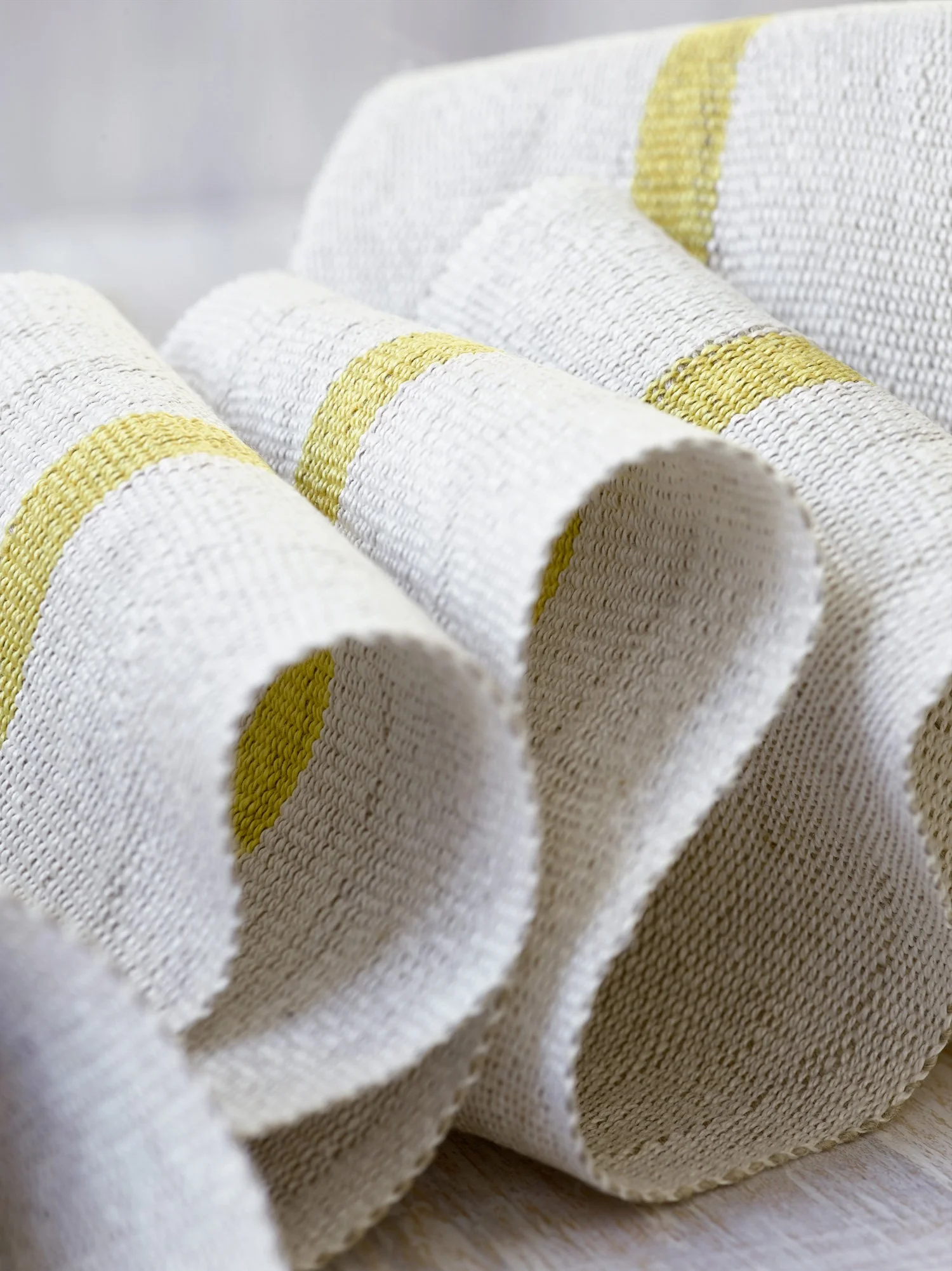 Close up of Fresh Yellow handwoven linen tape trim in a soft, bright yellow and white in wide width.