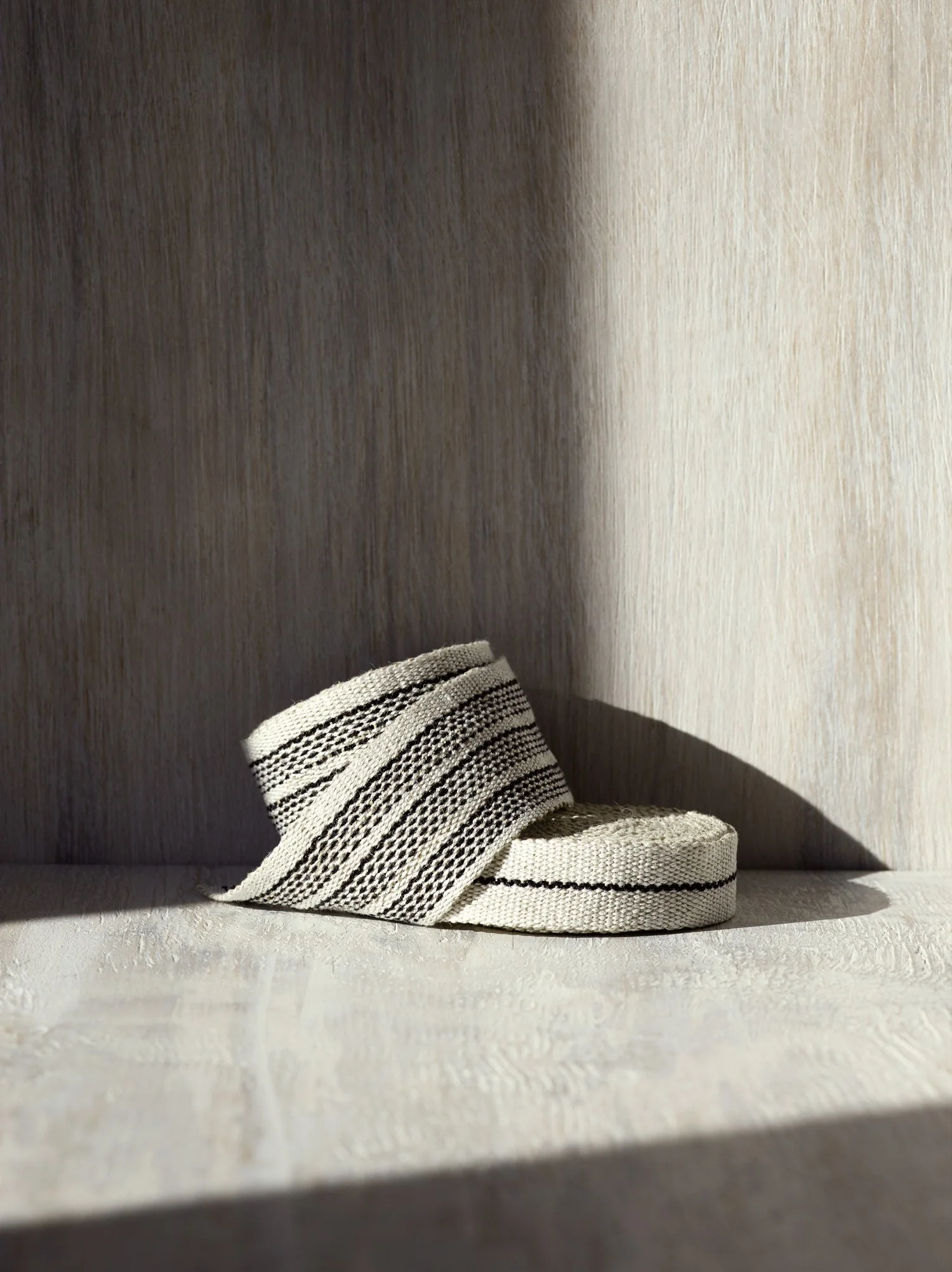 Stack of Agnes handwoven linen tape trim in crisp black and white in narrow and medium widths.