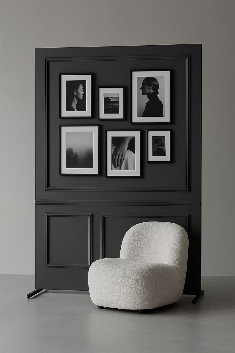 A modern interior scene featuring a black photo collage frame with seven black and white photographs, including profile portraits and natural landscapes, against a light gray wall. In front of the frame is a white, textured, rounded armchair.