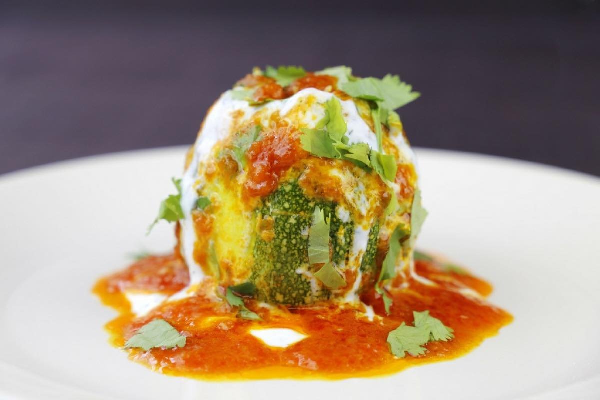 Dolma de courgette farcie avec sauce tomate et coriandre sur une assiette blanche