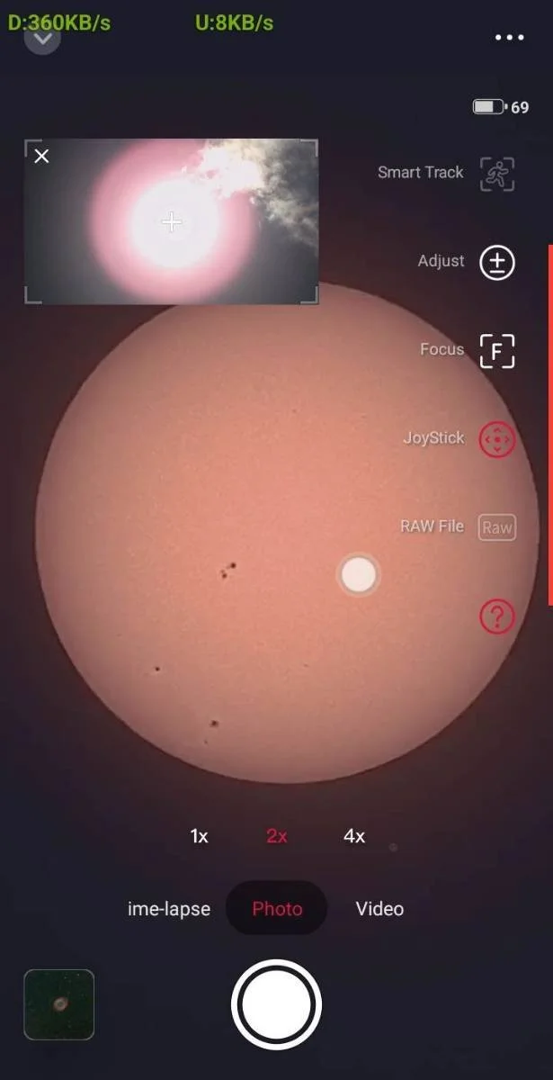 Screenshot of a solar telescope app displaying a view of the sun with sunspots. The app interface shows options for photo and video capture, zoom levels, and editing tools.