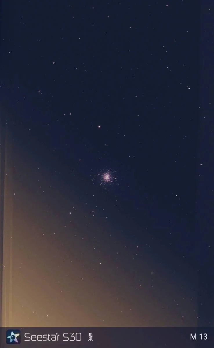 Night sky filled with stars and a bright star cluster or galaxy visible in the center.