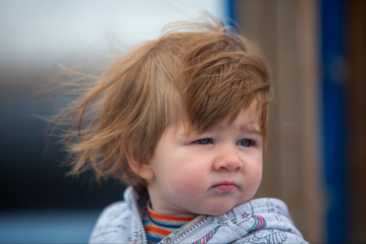A young child with messy, reddish-brown hair and a sad or upset expression.