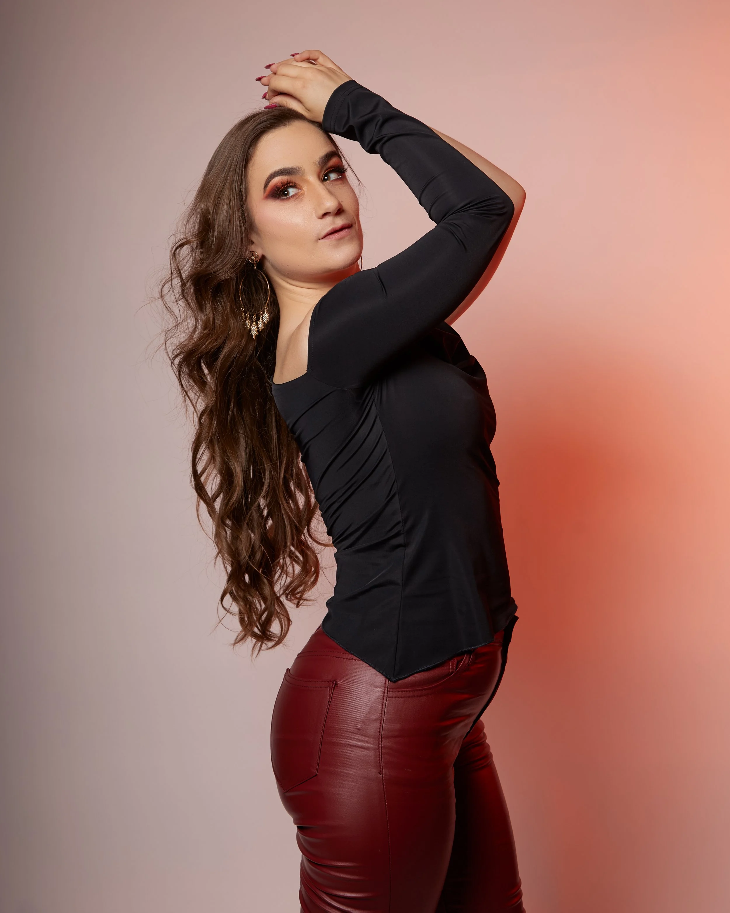 Cat Rojo looking over her shoulder and wearing a black top and red pleather pants