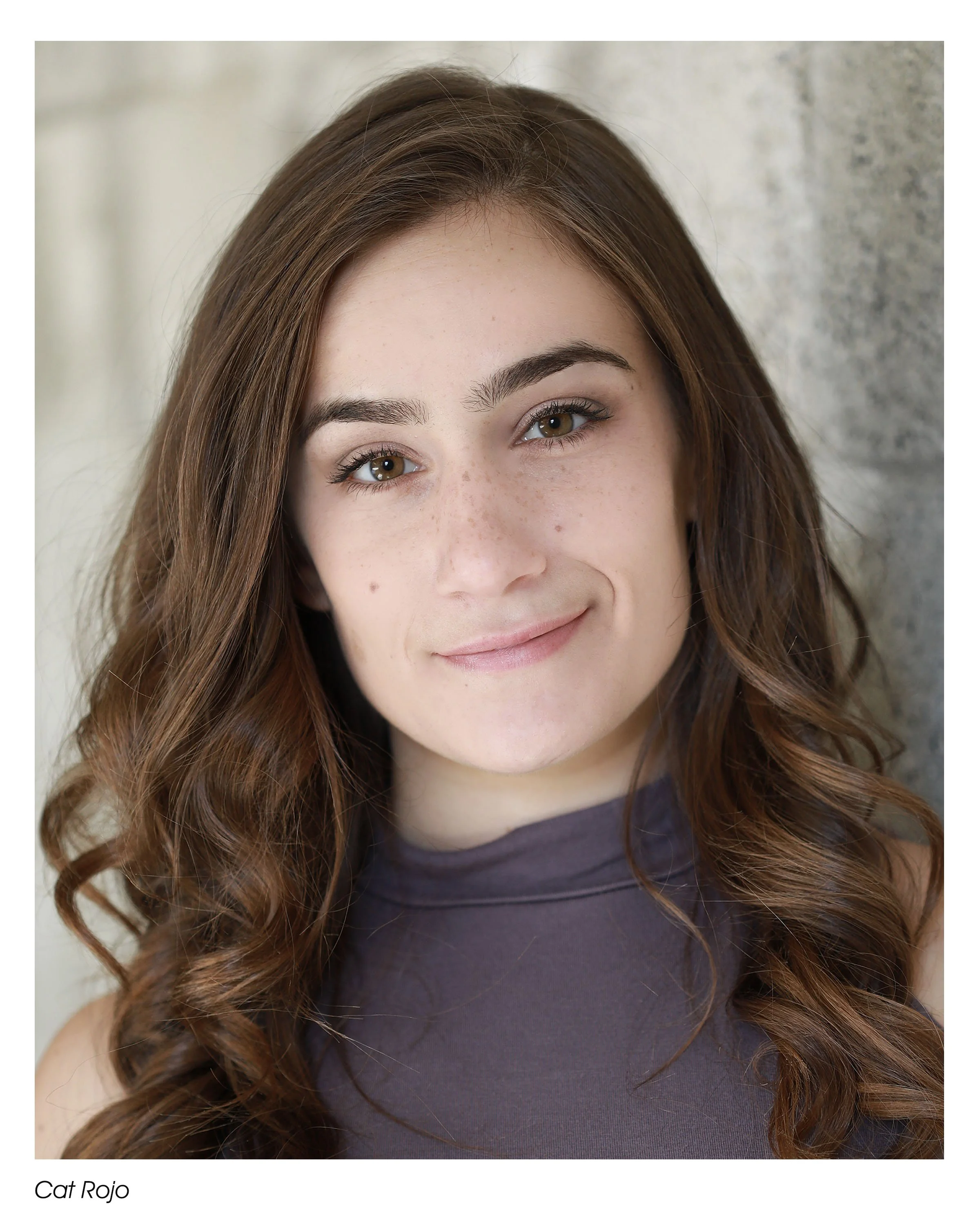 Cat Rojo close up headshot wearing a purple top with a soft expression