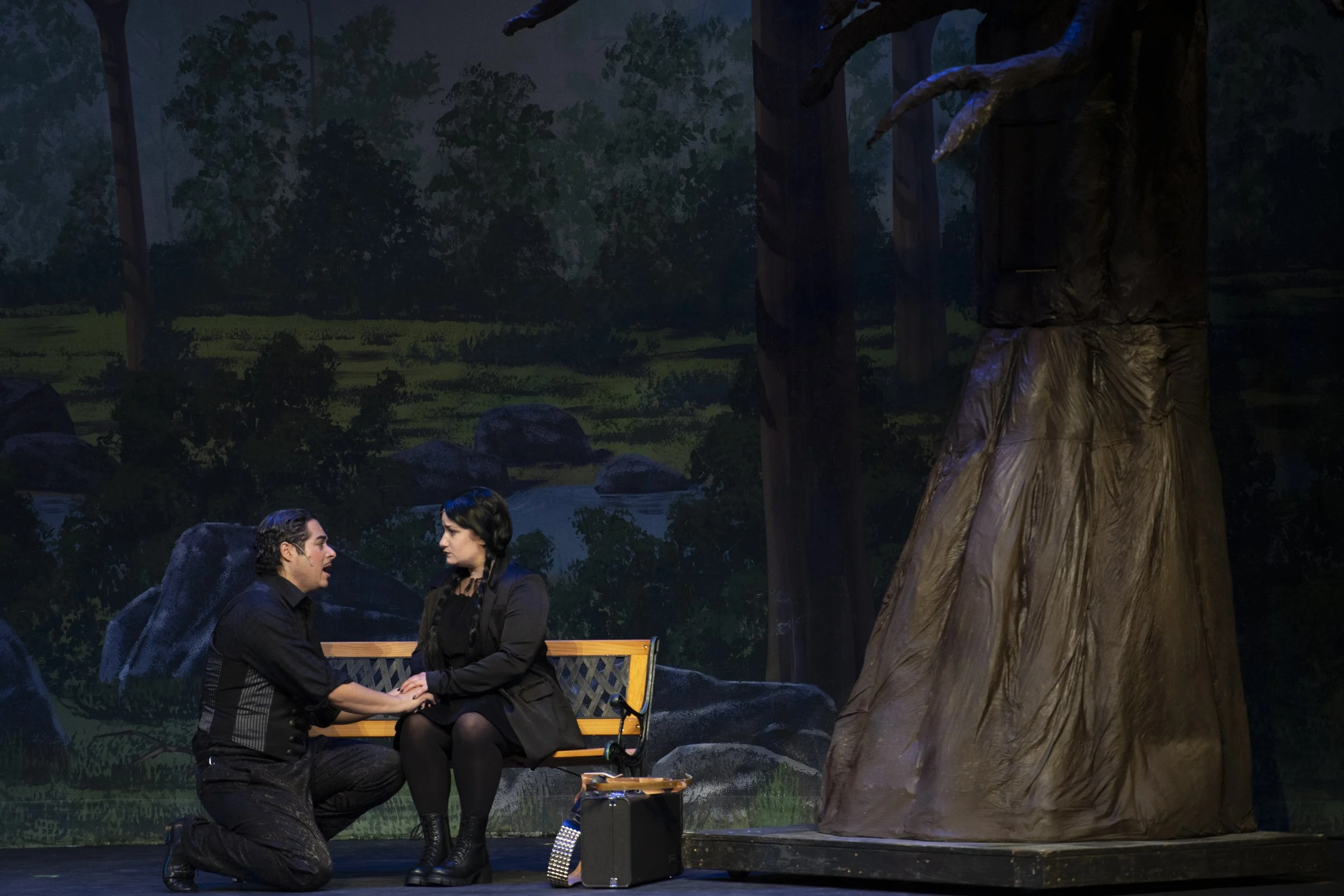 Cat Rojo as Wednesday Addams holding Gomez Addam's hand on a bench