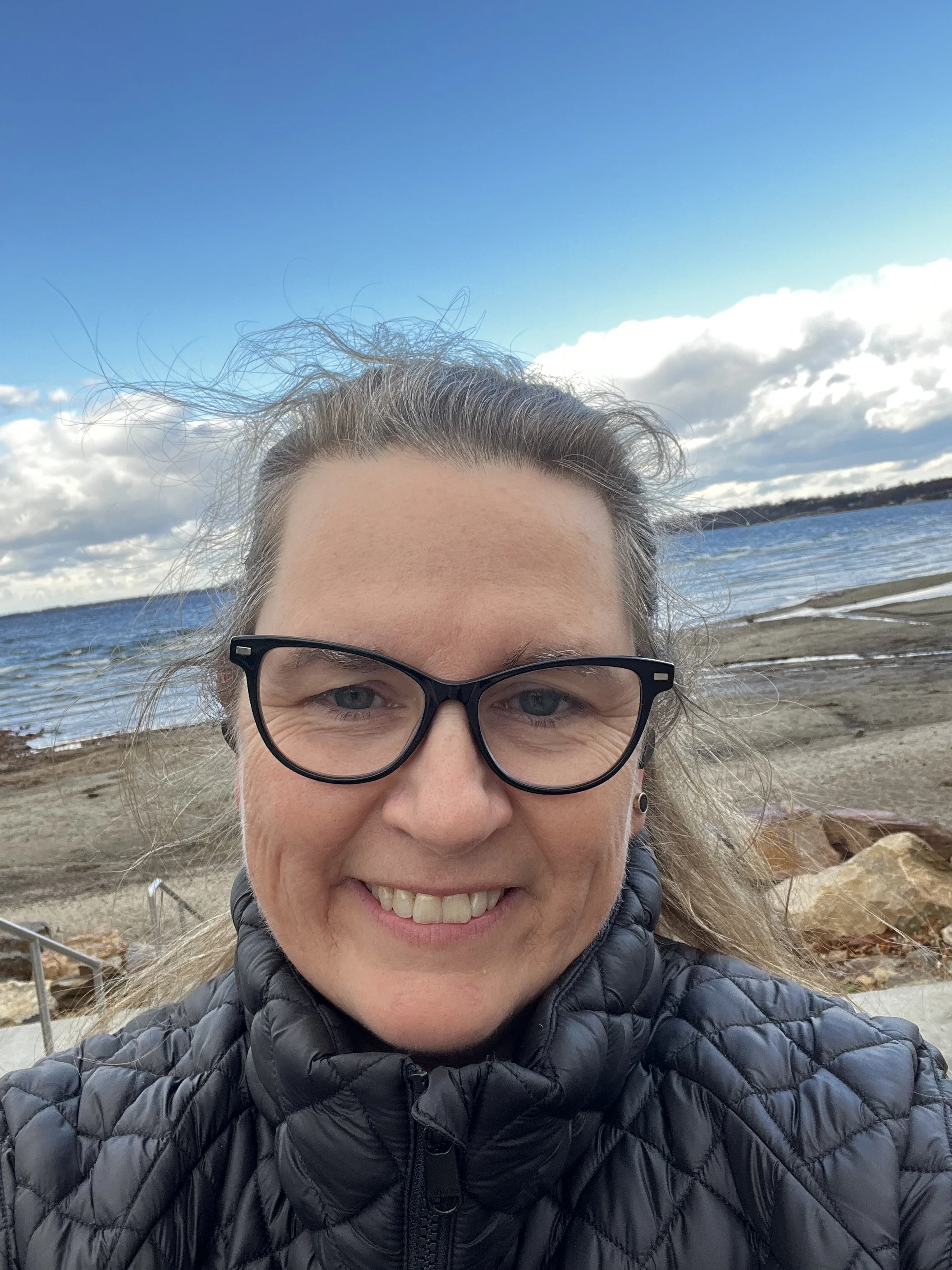 Gisèle Poirier Goetsch, grief therapist, smiling outdoors by the lake in Burlington, Vermont