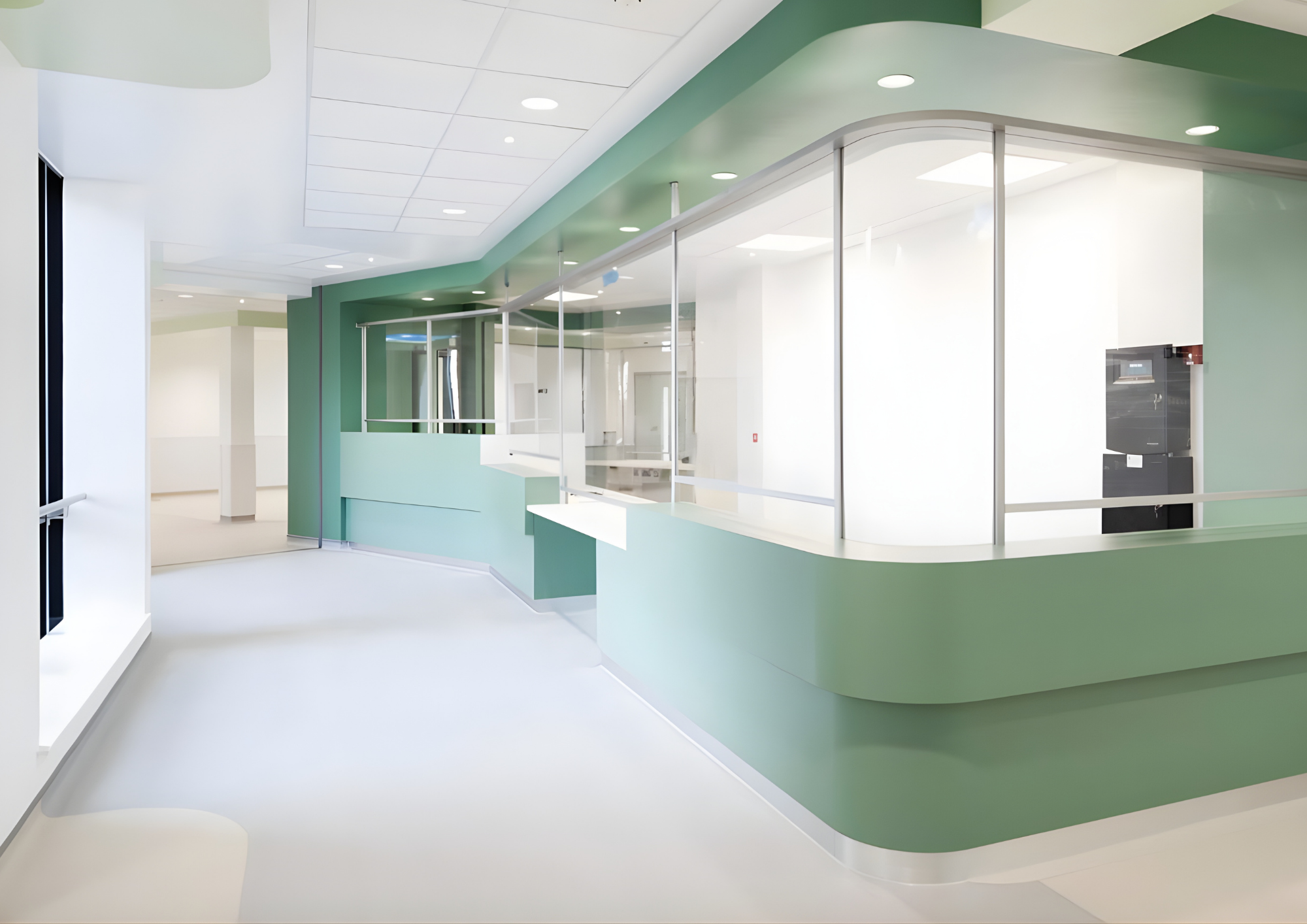 Empty modern hospital reception area with green and white walls, glass partitions, and a black vending machine in the background.