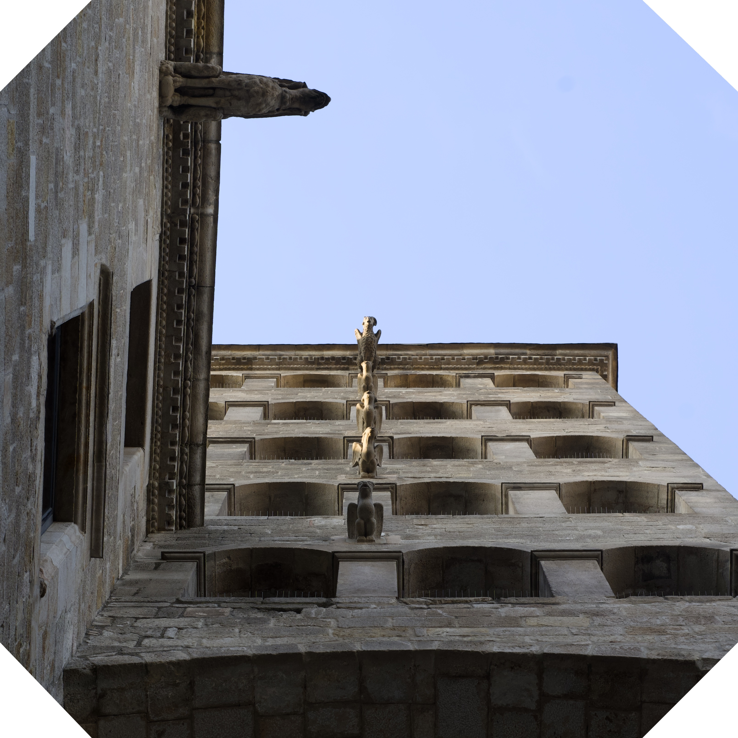Detalle de una estructura de piedra antigua con esculturas y elementos decorativos, vista del cielo despejado.