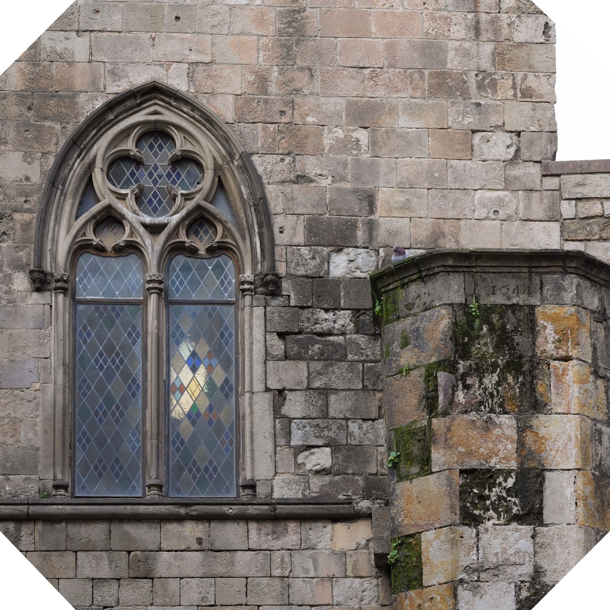 Ventana gótica de vidriera en una pared de piedra de una iglesia antigua.