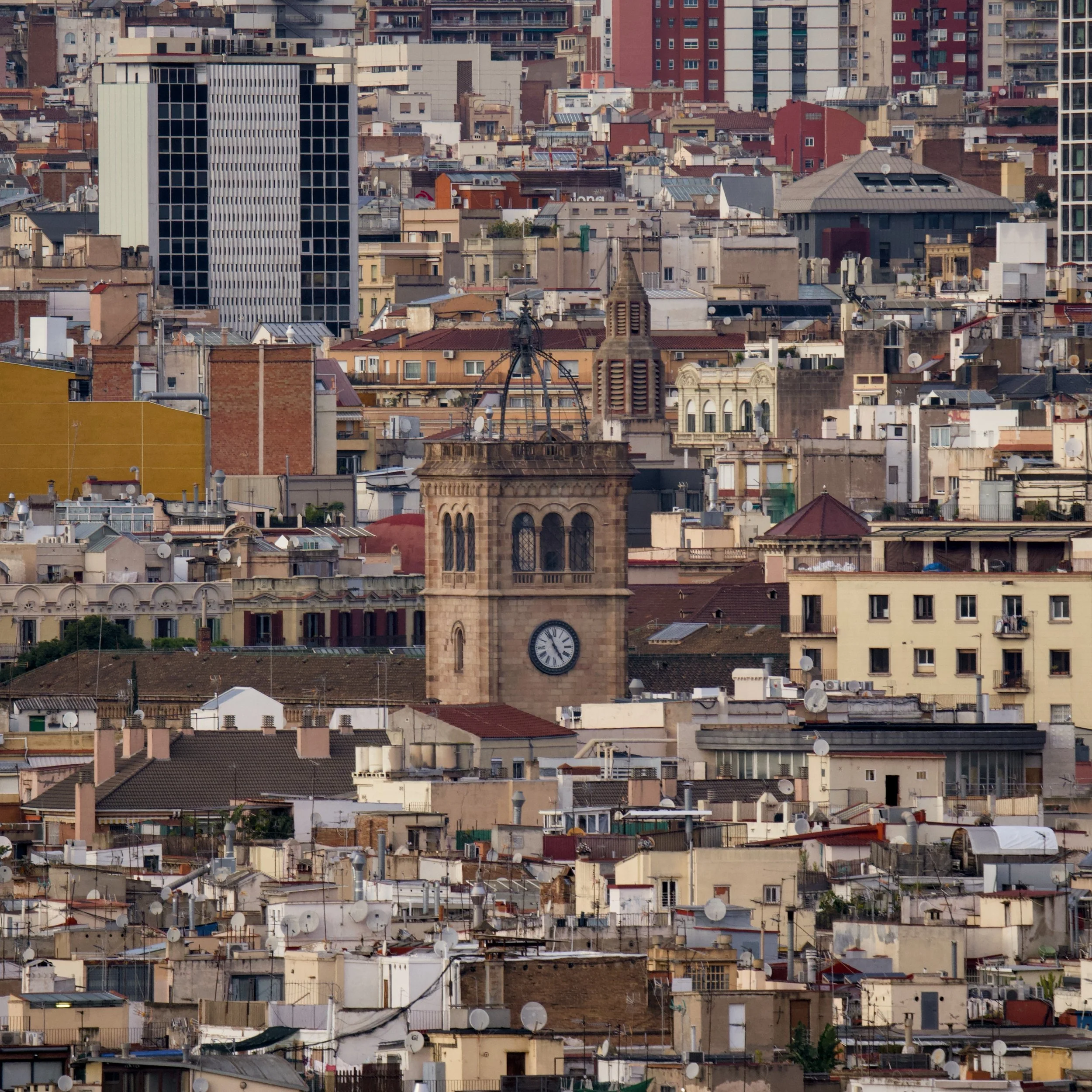 Vista de una ciudad con edificios residenciales y comerciales de diversos estilos y alturas, con muchas antenas y satélites en los techos, en un día despejado.