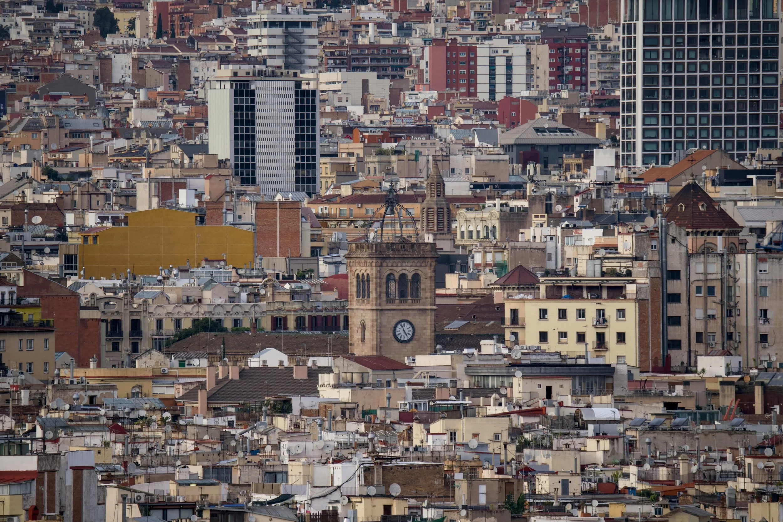 Paisaje urbano con edificios altos y casas en una ciudad densamente construida, incluyendo una torre con reloj.