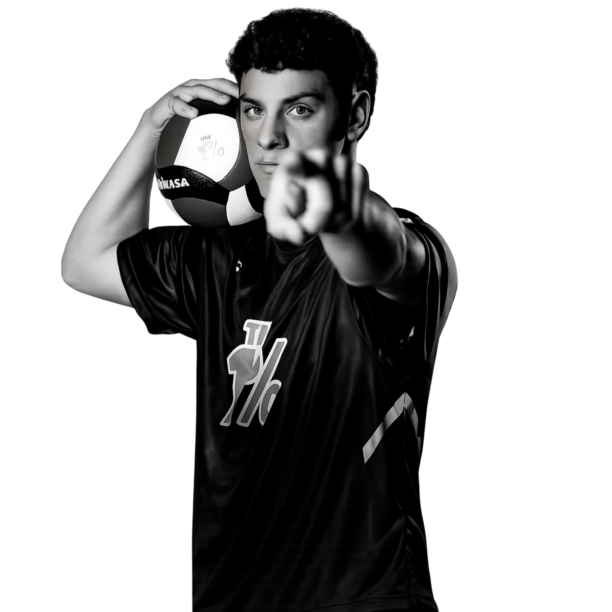 Black and white photo of a young man holding a volleyball near his head, pointing with his finger at the camera, with a serious expression.