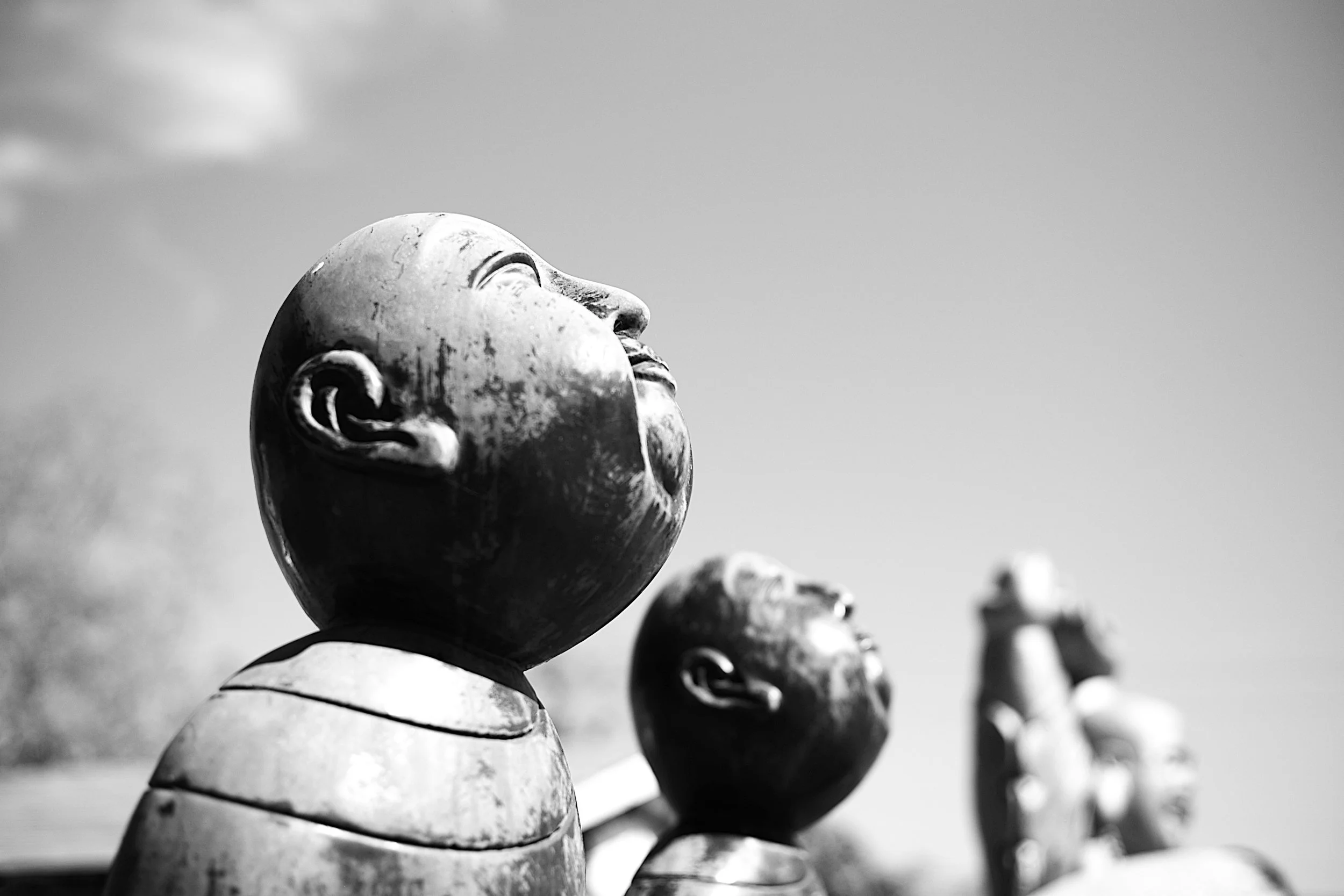 Black and white photograph of twin buddhas looking up into the sky with the sun on their face at Eastham Cape Cod