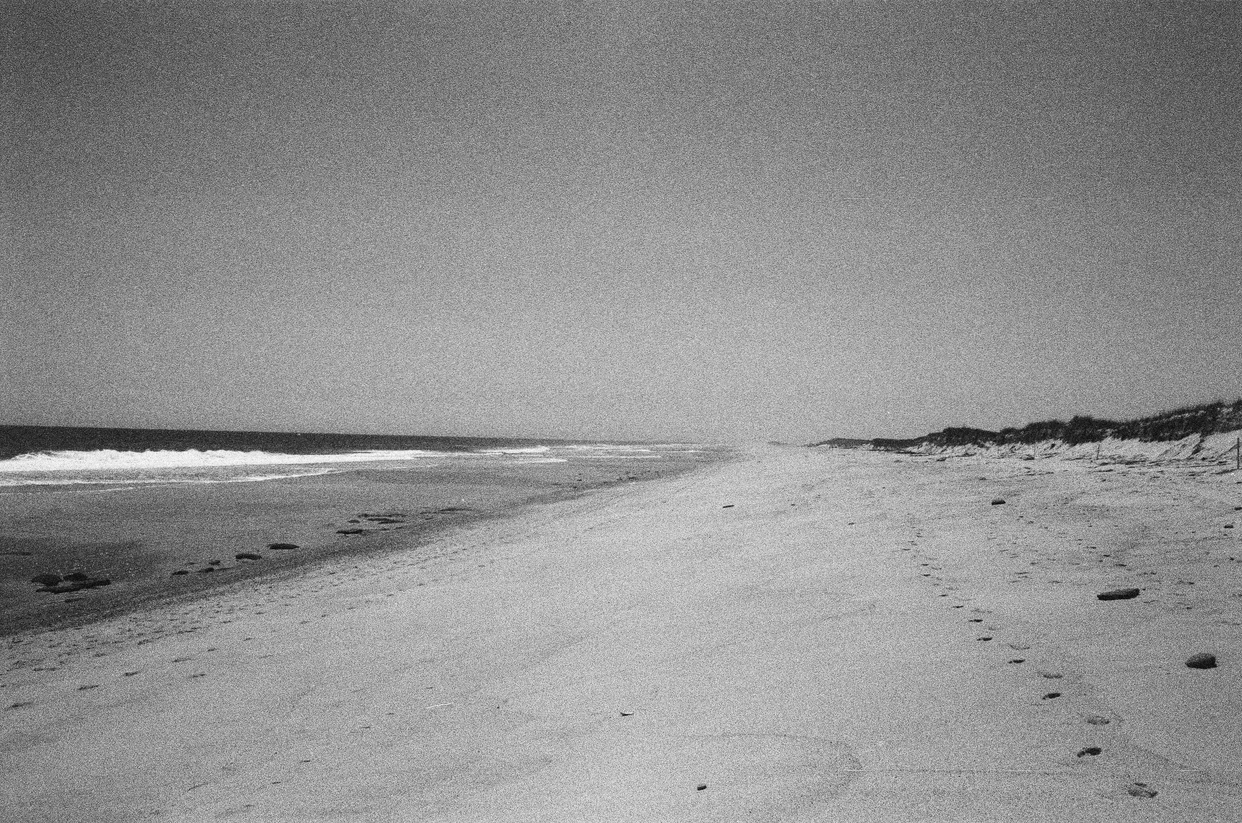 Black and white grainy photograph of Nauset beach in the fog and the beach and ocean disappearing into a vanishing point.