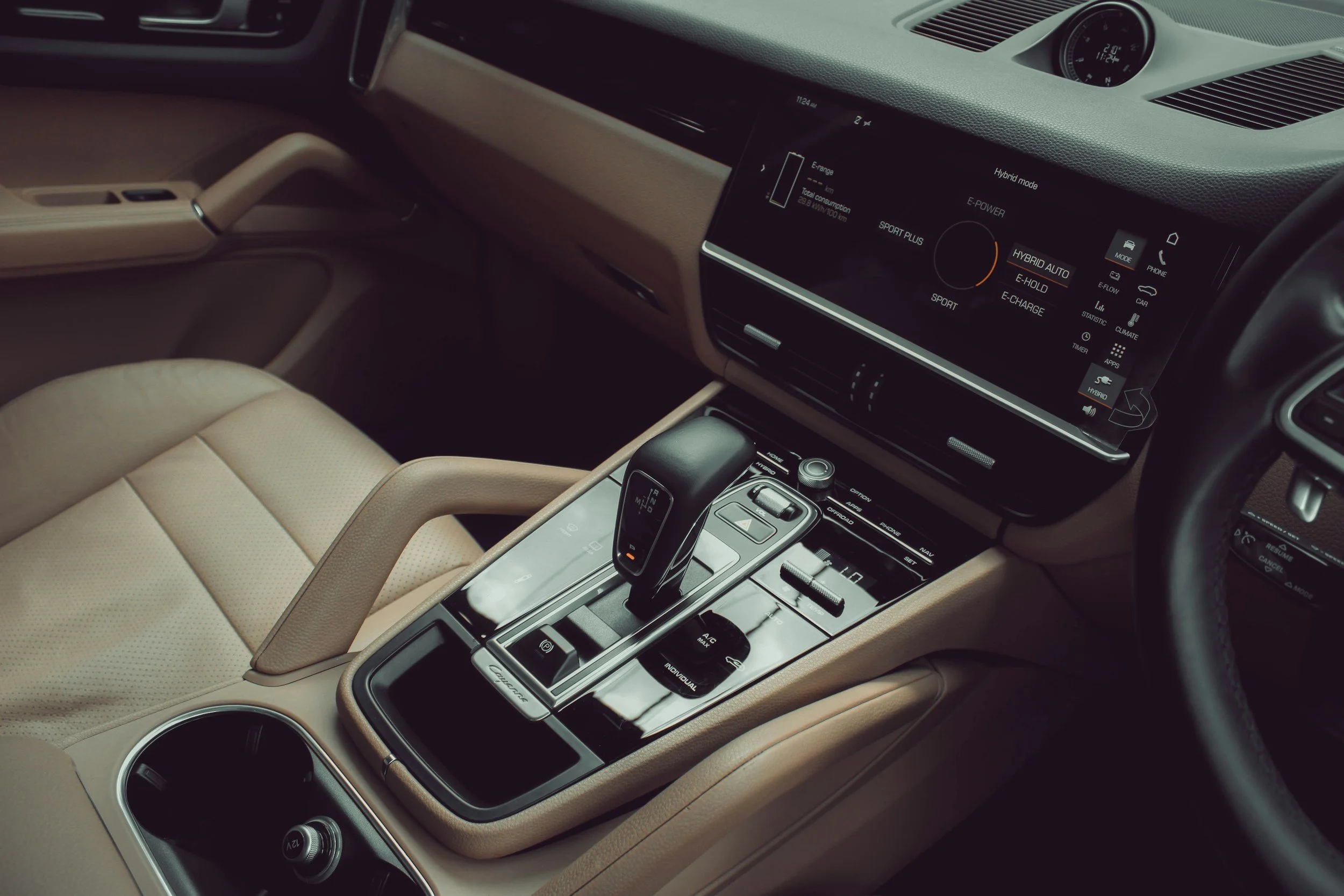 The interior of a car showing the beige leather driver's seat, center console with gear shifter, control buttons, and a digital display screen on the dashboard.